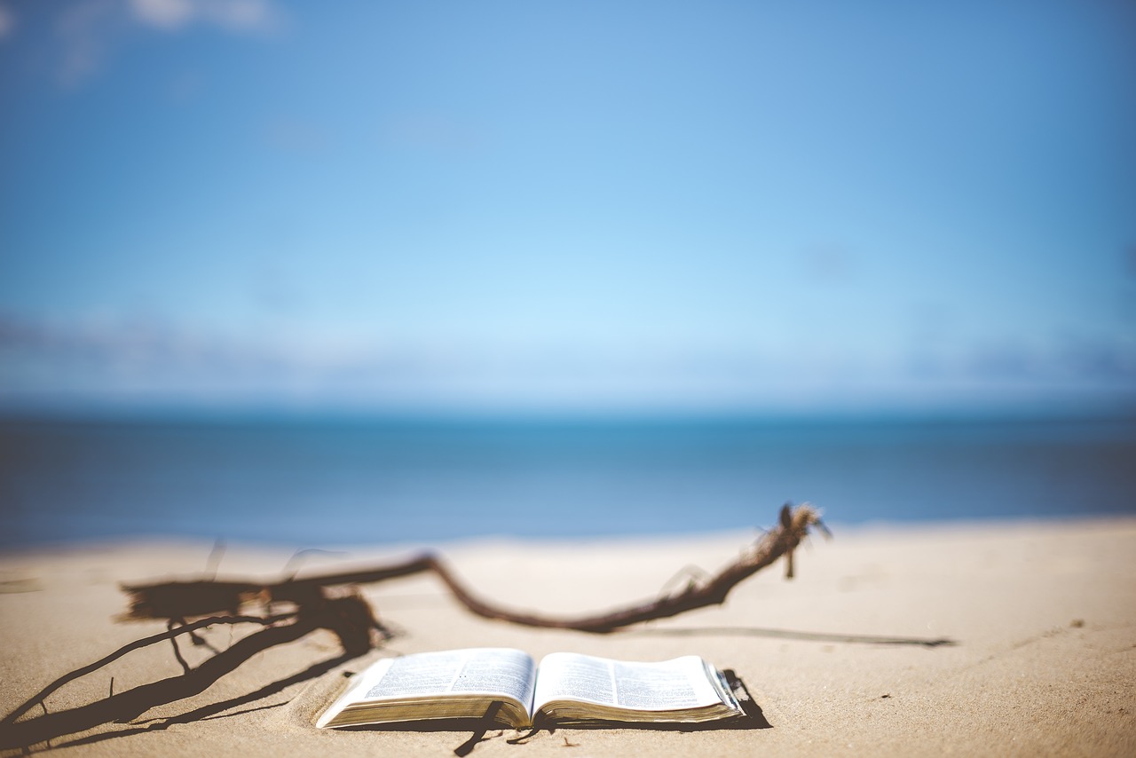 Picture of a Bible on the beach with a beautiful ocean behind it